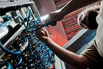 Technician connecting cables of server in data center
