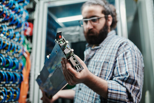Hand on technician holding machine part in server room