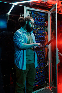 IT engineer using laptop by servers in data center