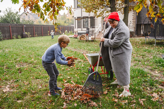 Mother with son raking dry leaves in back yard
