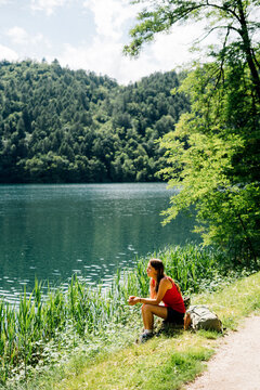Woman spending leisure time sitting near Lake Levico on sunny day