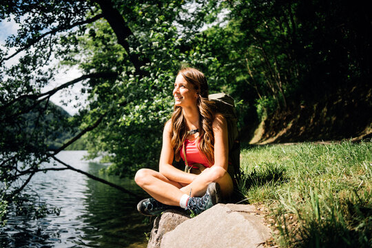 Happy woman sitting cross-legged near Lake Levico