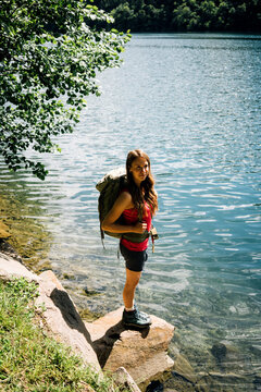 Woman with backpack standing on rock near Lake Levico
