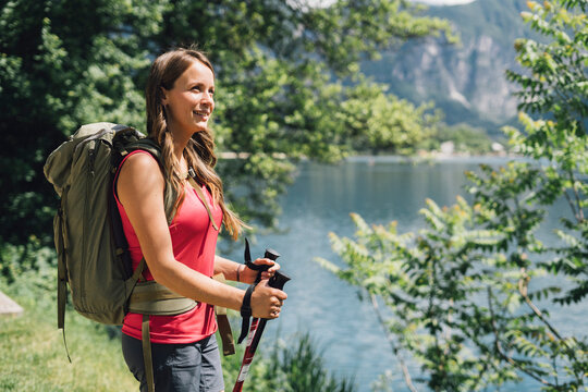 Thoughtful young hiker with backpack and hiking poles