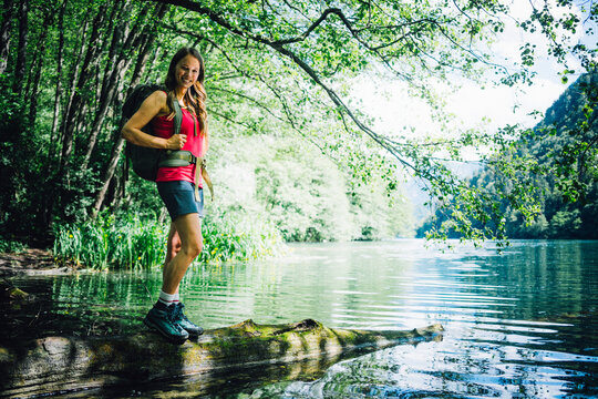 Happy woman standing on log at Lake Levico