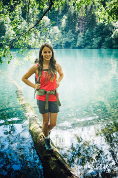 Smiling hiker walking on tree log by Lake Levico