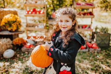 Smiling girl holding pumpkin at autumn fair on sunny day
