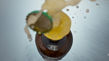 Uncorking bottled craft beer closeup. Unfiltered liquid splashing from flask