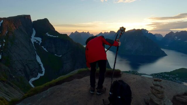 Asian tourist setting up his camera on a scenic peak of Reinebringen to take photos