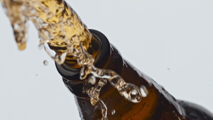 Uncorking glass beer bottle closeup. Foamy carbonated cider pouring from flask