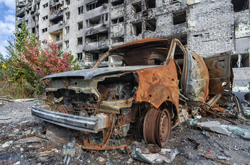 Fototapeta premium burnt blown up car against the background of a destroyed house in Ukraine