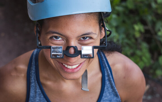 Happy brown woman wearing belay glasses and helmet