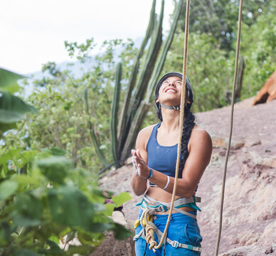 Smiling woman who rock climbs looking up with chalk on hands
