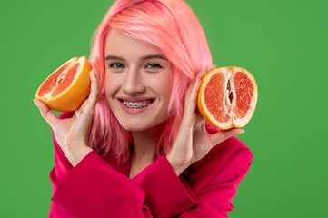 Cheerful woman with citrus fruit posing against the green background