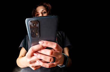young woman hand using mobile phone or smartphone on black background