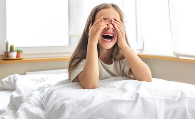 Portrait of a charming little girl in bed early in the morning.