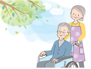 車椅子のシニア男性を介助するシニア女性