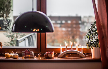 Decorated window sill with candles, a garland, a cup of fox, a toy deer.