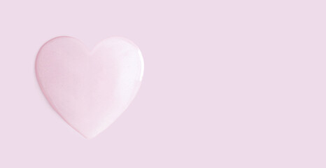 drop of cosmetic essence of serum gel on a light pastel background in the shape of a heart