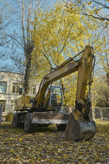 small excavator dug a trench in the ground in autumn background