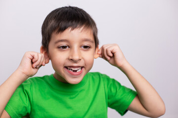 boy child in a green T-shirt is having fun on a white background in the studio without baby teeth.