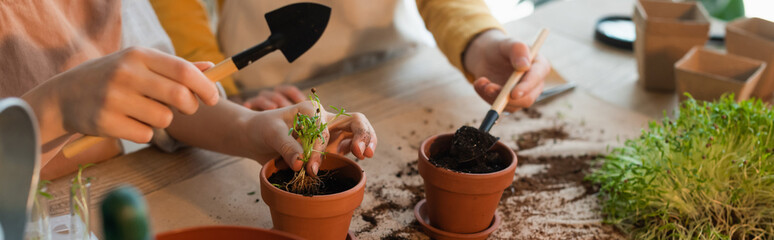 Cropped view of children with gardening shoves planting microgreen at home, banner.