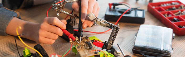 Cropped view of child making robotic model with millimeter at home, banner.