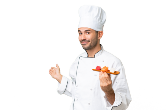 Young caucasian chef holding a sushi over isolated background extending hands to the side for inviting to come