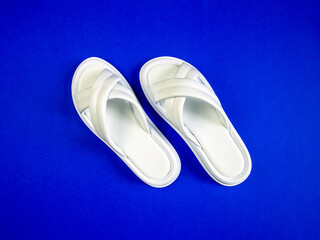 Women's summer white slippers on a blue background. Slippers. Horizontal image