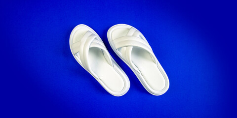 Women's summer white slippers on a blue background. Slippers. Banner for insertion into site. Place for text cope space.