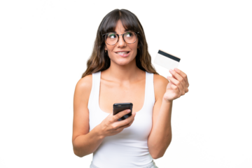Young caucasian woman over isolated background buying with the mobile with a credit card while thinking