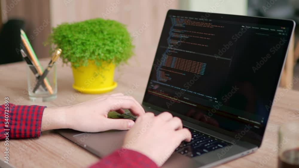 Wall mural close up of freelancer's hands typing code on laptop keyboard. camera slides around developer's fige
