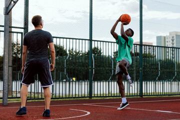 Professional basketball player with friends at basketball court showing skills training friends...