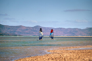 Two windsurfers practice in a lagoon in the Canary Islands