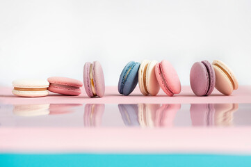 Cake macaron or macaroon on white and pink mirror background from above, colorful almond cookies, pastel colors, vintage card, top view