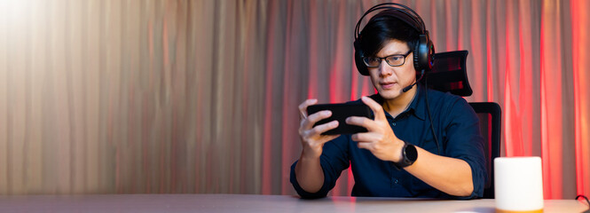 Asian man playing game on mobile phone. Professional gamer playing video games on personal pc...