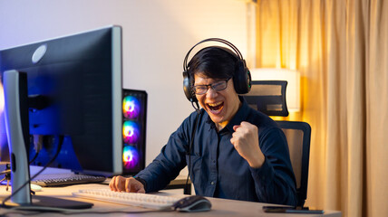 Happy Professional Asian male gamer playing video games on personal pc computer. Esport online game.