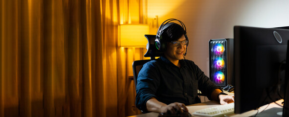 Happy Professional Asian male gamer playing video games on personal pc computer. Esport online game.