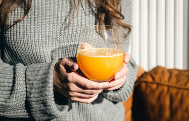Close-up, a glass of orange juice in female hands.