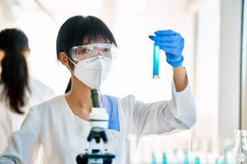 Female scientist looking at liquid in test tubes working in modern research laboratory