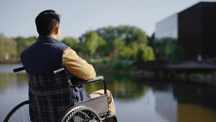 Back view of the disabled man on the pier looking at the water early in the morning in the local lake alone. People, rehabilitation and resting concept