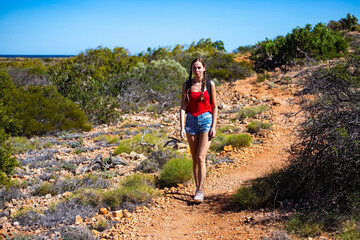 Naklejka premium cute tanned girl in short shorts hiking through a gorge in cape range national park in western australia; hiking in the australian outback near exmouth