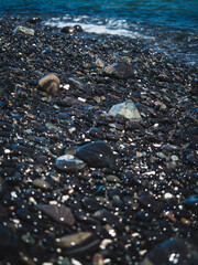 Scenic close up view of Koh Hin Ngam Island iconic black round pebble stone beach. Near Koh Lipe Island, Tarutao National Marine Park, Satun, Thailand. Selective focus, blurred foreground.