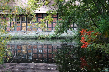 Spiegelung eines schönen alten Fachwerkhaus vom Kleinen Teich am alten Meierhof Heepen am Leithenhof an der Lutter im Herbst in Bielefeld am Hermannsweg im Teutoburger Wald in Ostwestfalen-Lippe - obrazy, fototapety, plakaty