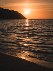 Scenic view of Sunset Beach, Koh Lipe Island. Dramatic sunset orange sky with sunlight reflection on sea water waves. Satun, Thailand.