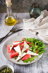 Homemade salad of feta cheese, watermelon and arugula on a plate. Organic diet. Vertical view