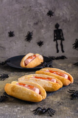 Halloween recipe for hot dogs with sausage fingers in ketchup on a slate on the table. Vertical view