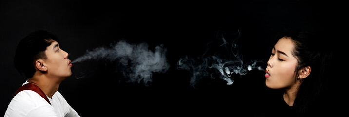 Dark and sullen shot of  young male and female smoking over a black background.Close up Man with...