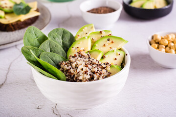 A bowl of quinoa, avocado and spinach on the table. Organic diet.