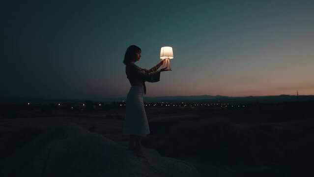 Silhouette of a woman holding a lamp at sunset